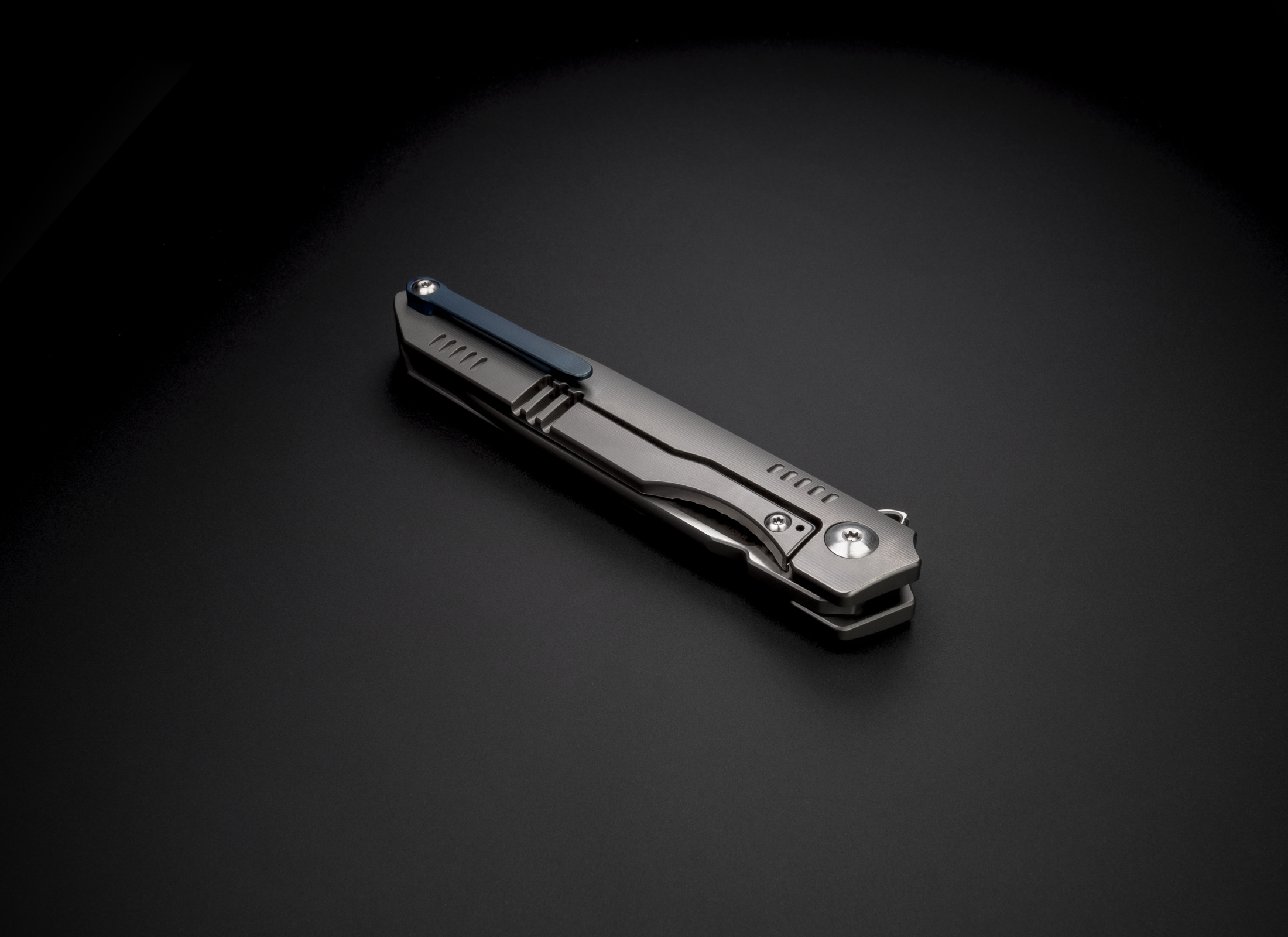 The Alta by Korcraft, titanium handle and m390 blade closed with pocket clip on black background