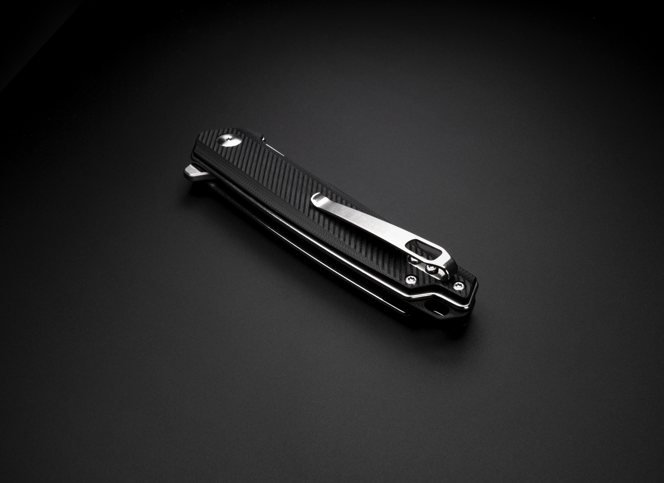 The Bellum by Korcraft Black pocket knife closed with pocket clip on black background