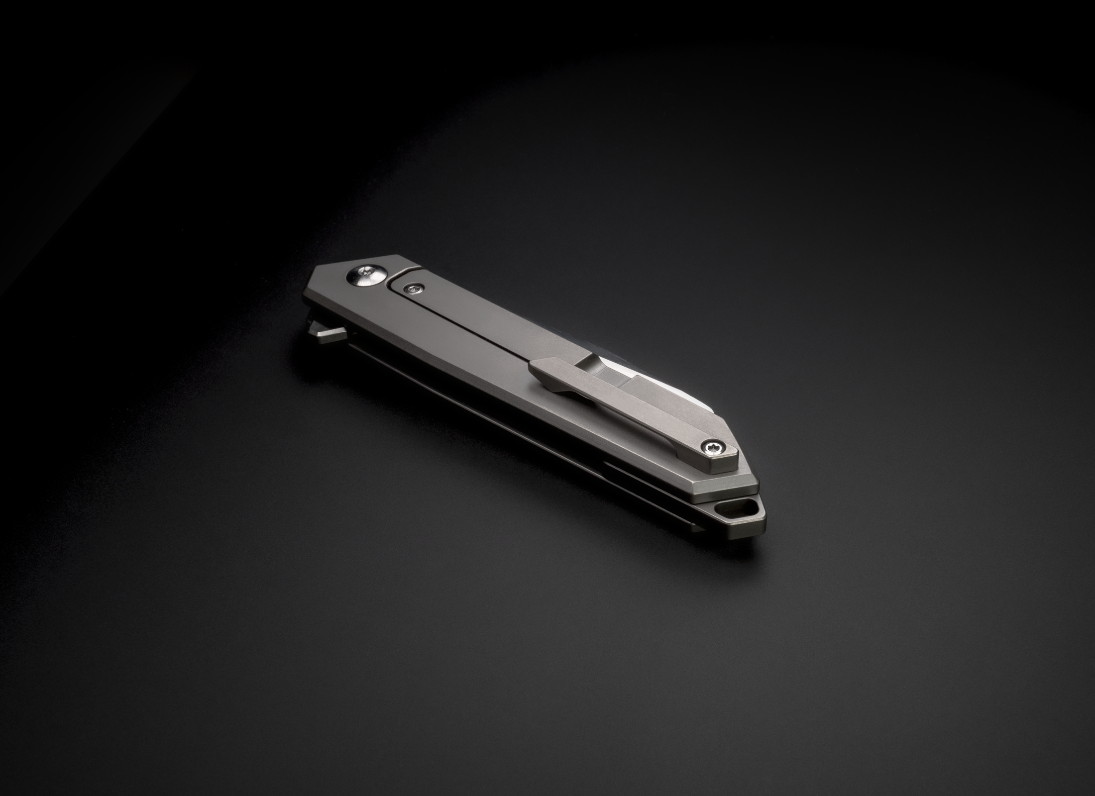 The Rixa by Korcraft, titanium handle and D2 blade pocket clip closed on black background