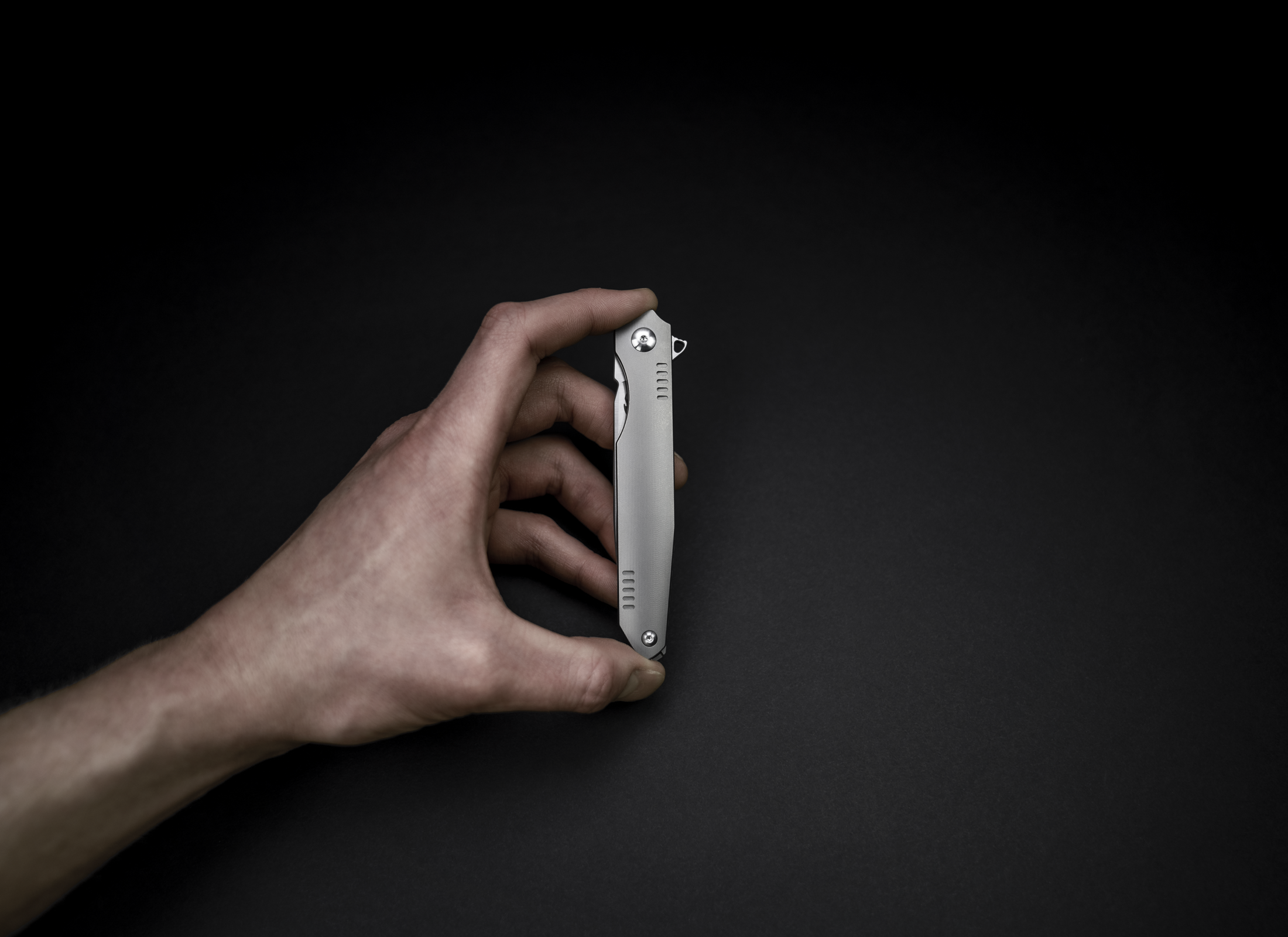 The Alta by Korcraft, titanium handle and m390 blade closed held in hand on black background
